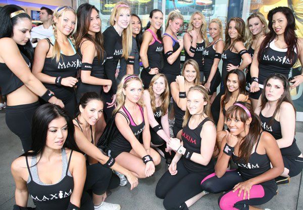 Group of women in black tank tops and workout gear pose for a photo in front of a building.