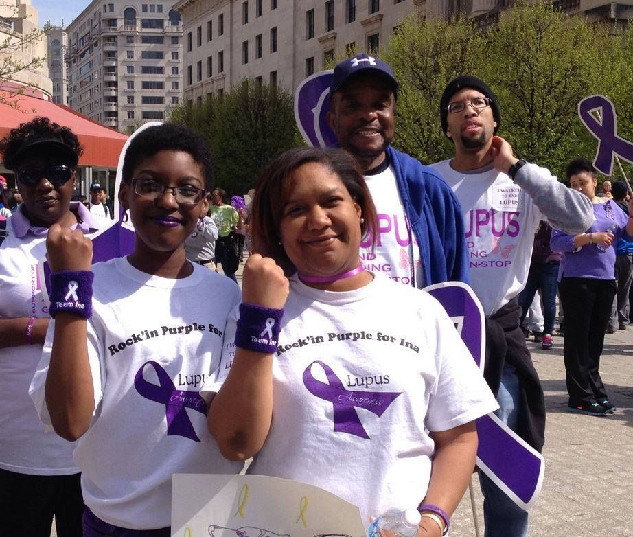 Group of people in purple, raising fists, at a Lupus awareness event.