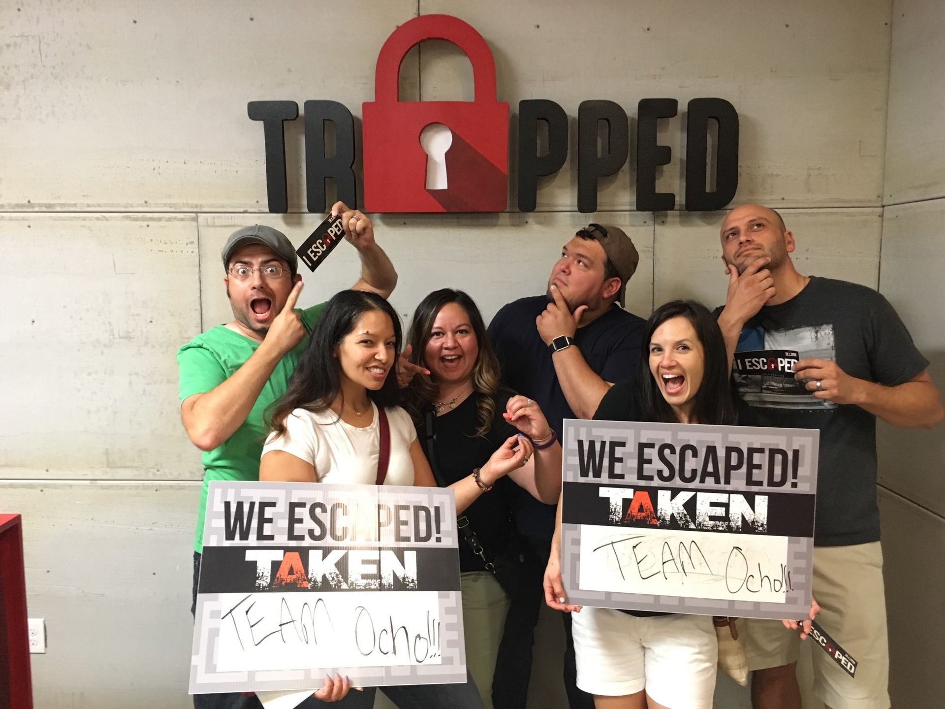 A group of people are posing for a picture in front of a sign that says trapped.