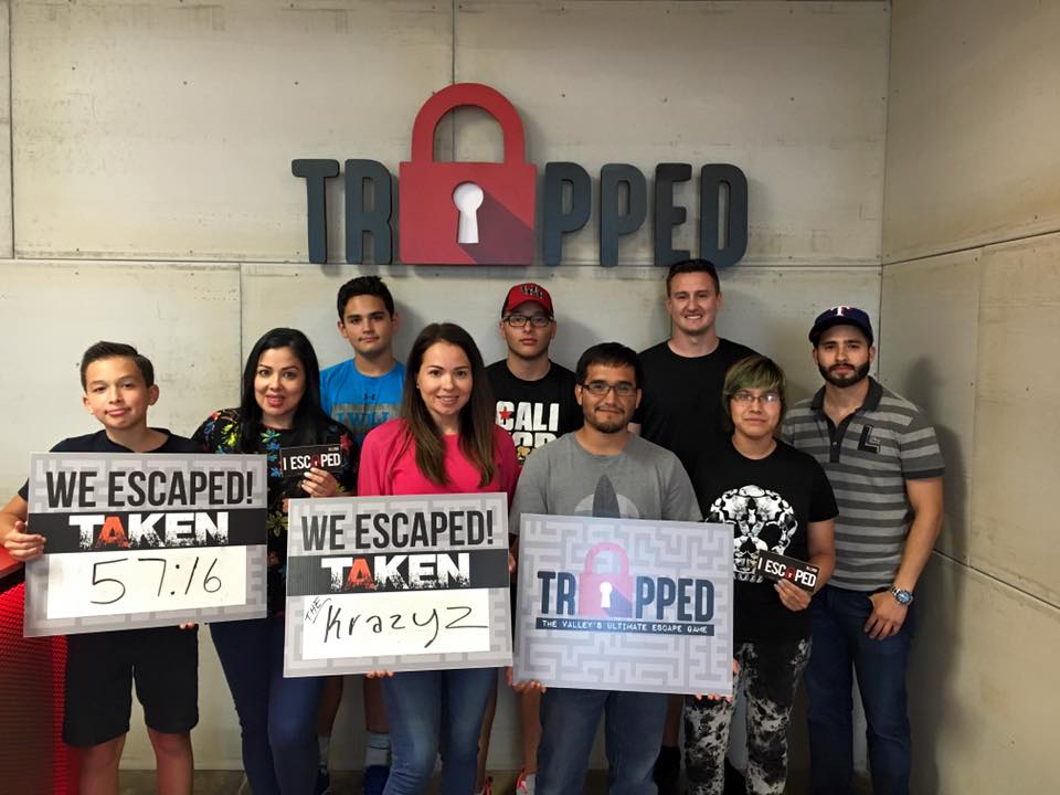 A group of people are posing for a picture in front of a sign that says trapped.