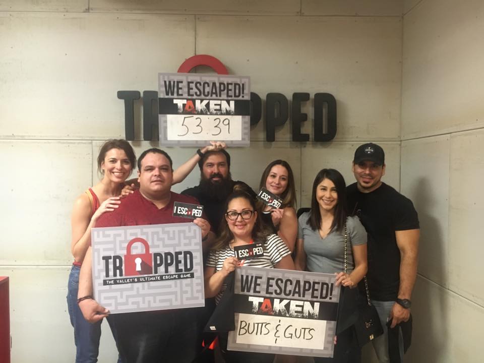 A group of people are posing for a picture in front of a wall that says trapped.