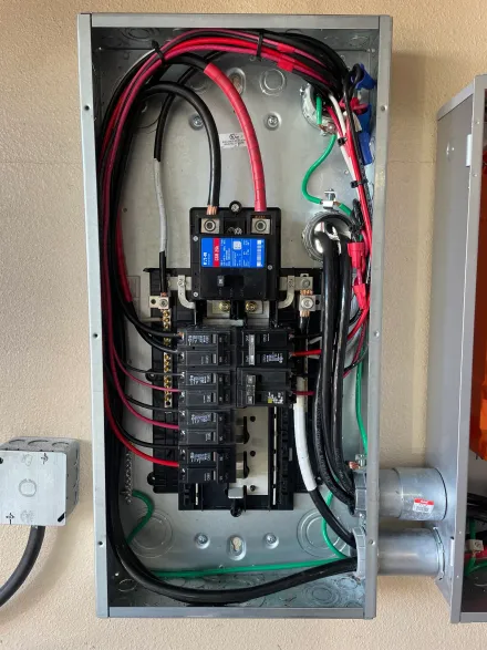 Open electrical panel with black and red wires, circuit breakers, and a digital display.