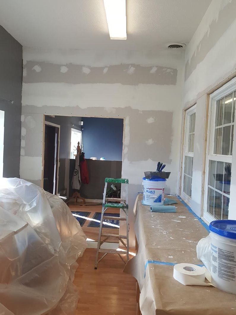 A room with a table and a ladder in it is being painted.