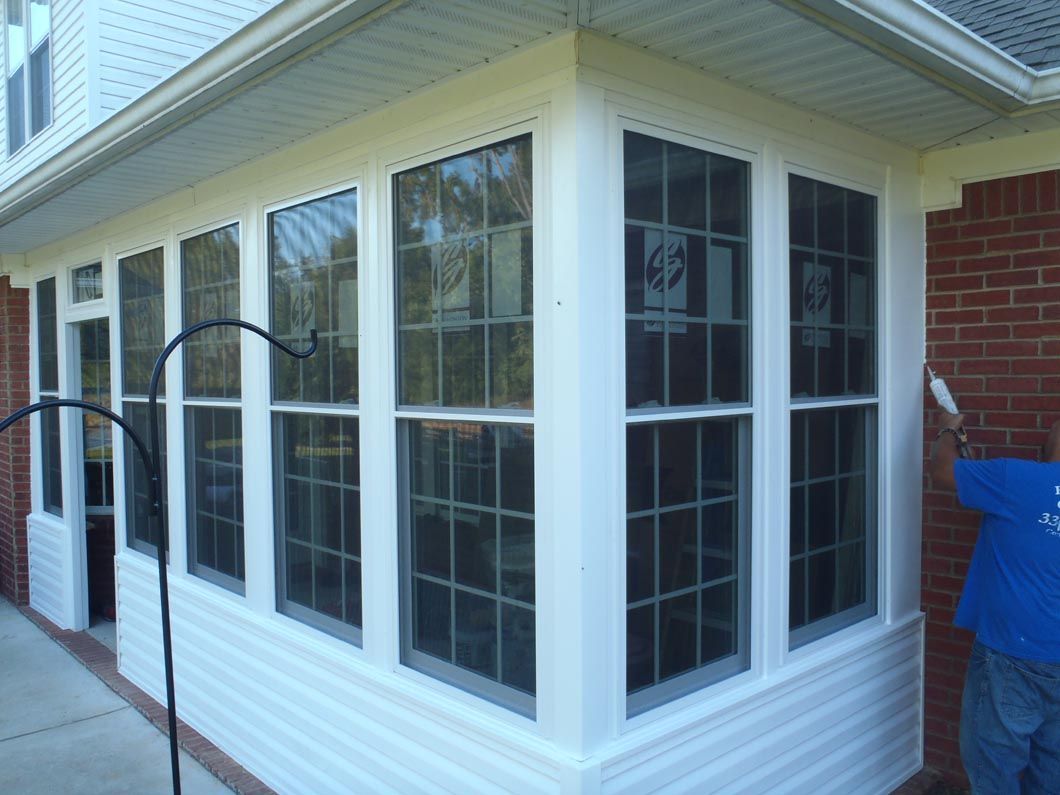 A man is standing in front of a house with a lot of windows.