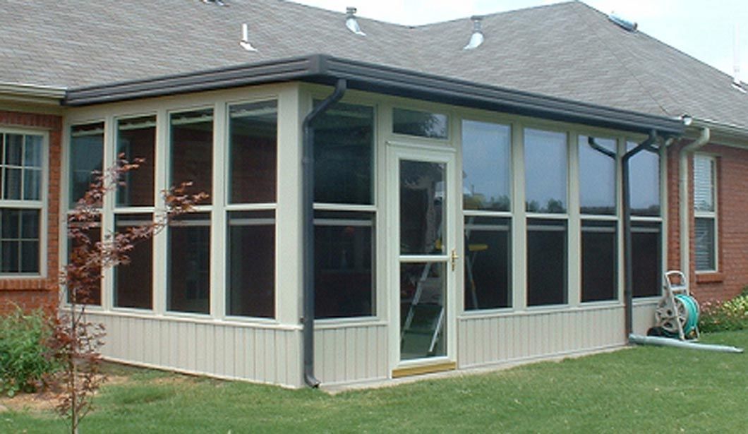 A screened in porch on the side of a brick house.