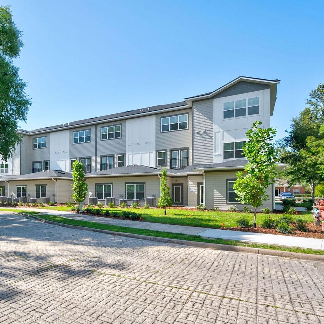 A large apartment building with a lot of windows and trees in front of it.