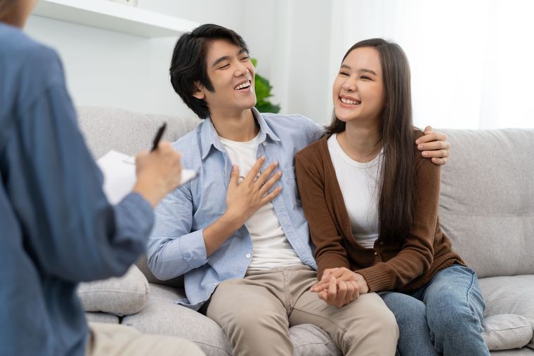 Two people smiling on a couch during a counseling session