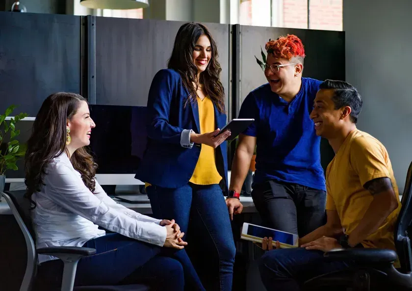 group of marketers working together and smiling in an office space.
