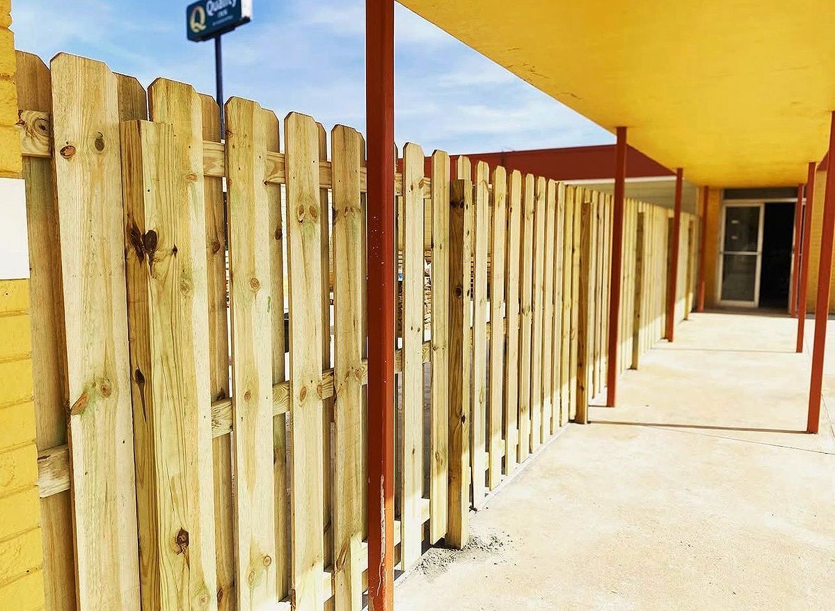 Wooden fenced walkway with red posts under a yellow awning beside a building