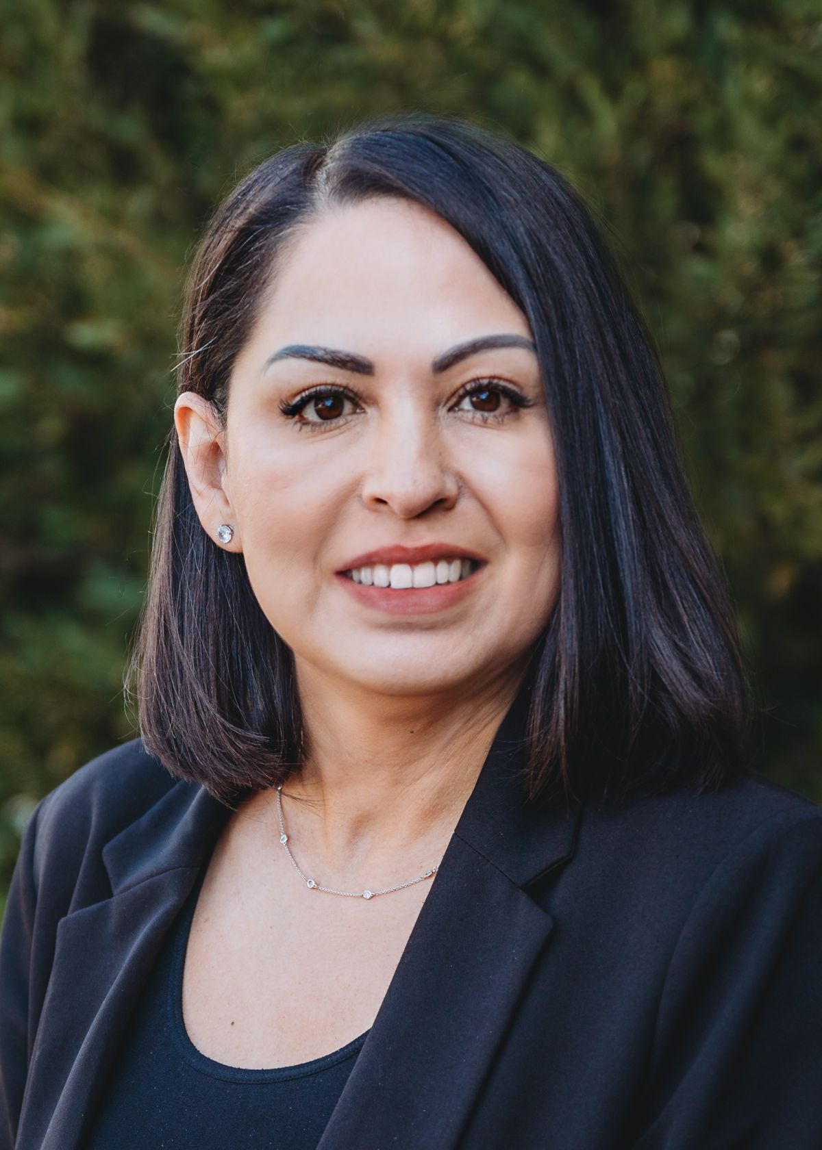 A woman with long dark hair is smiling for the camera.