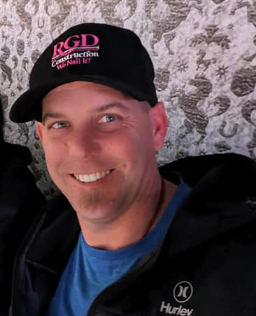 A man wearing a hat that says rgd construction on it