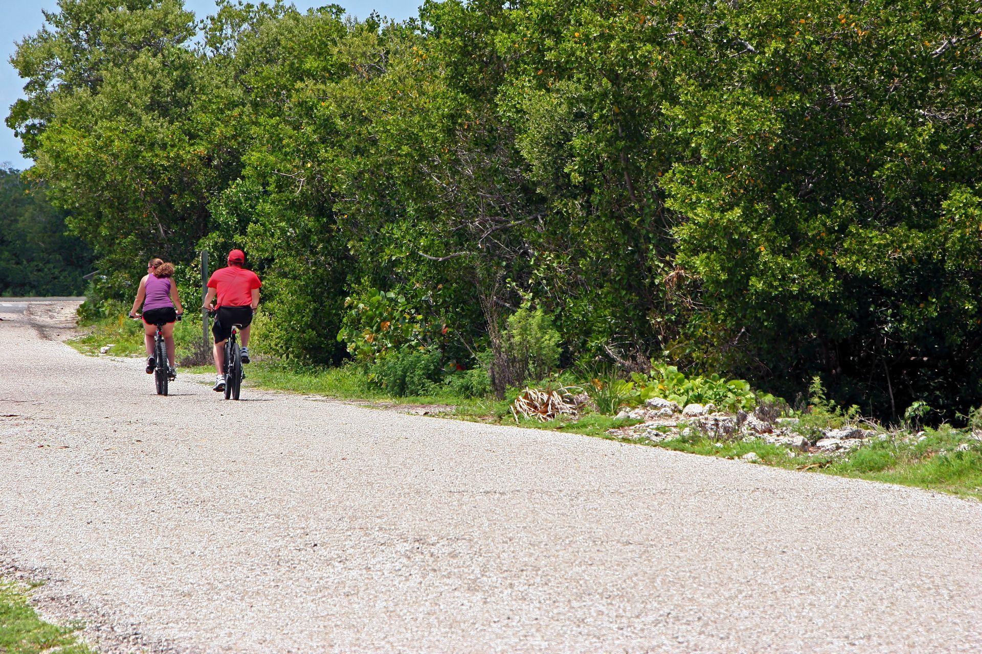 Two people are riding bikes down a gravel road, representing the topic of Florida bicycle laws.