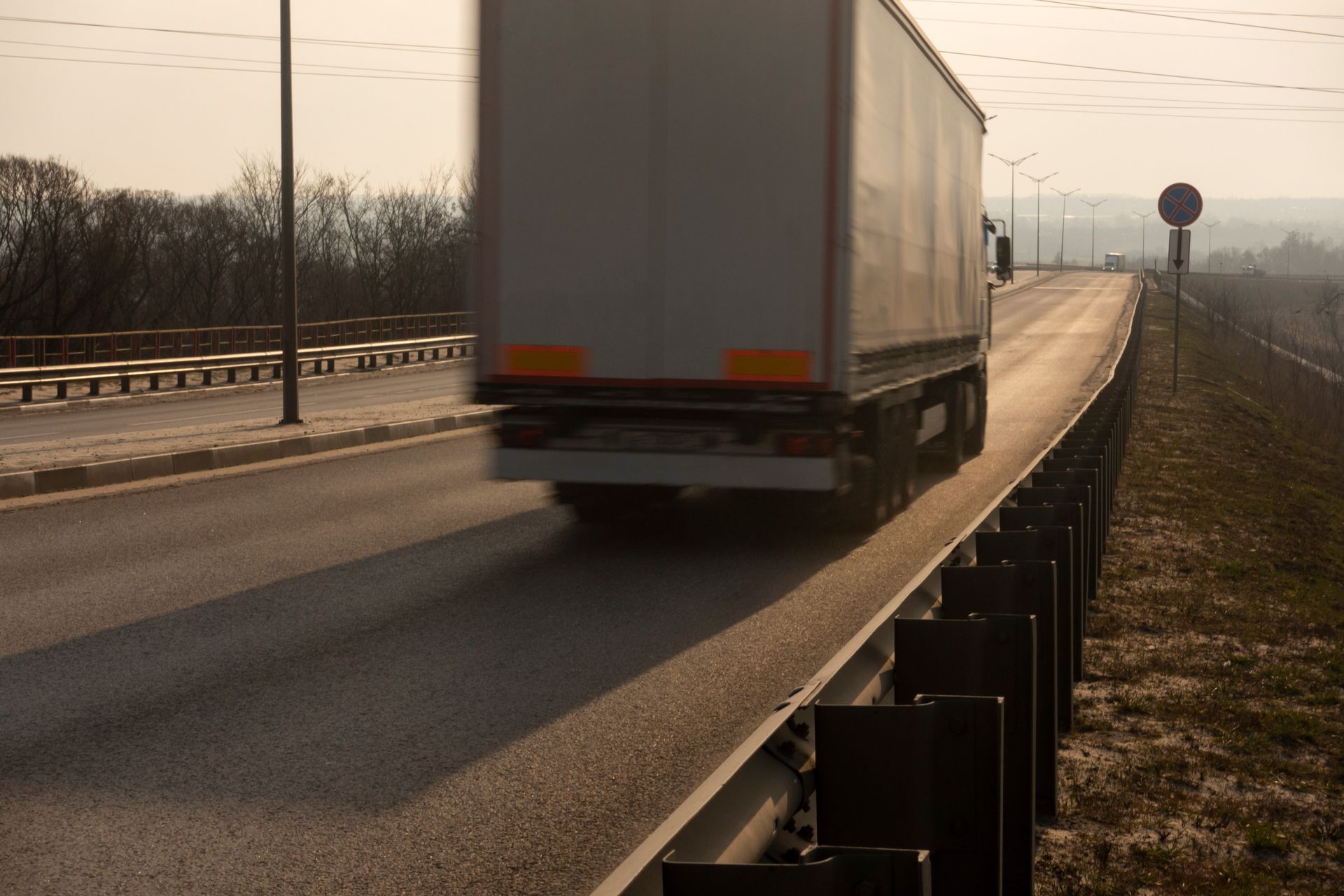 A white semi truck is driving down a highway, representing the topic of Florida truck driver fatigue.