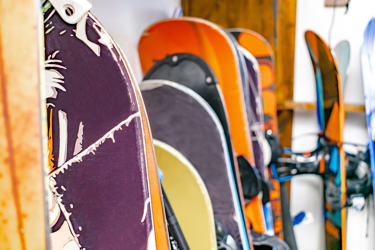 Una fila de tablas de snowboard colgadas en un estante de madera.