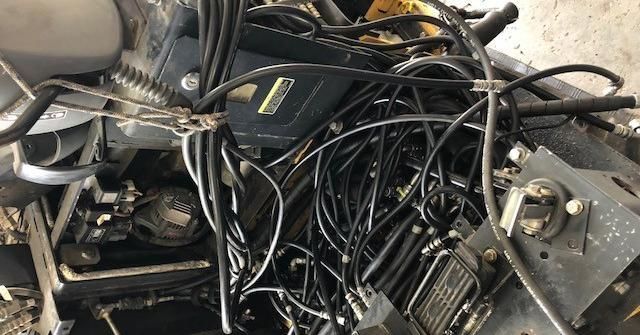 Tangled black hoses and wires on machinery, possibly an engine compartment.