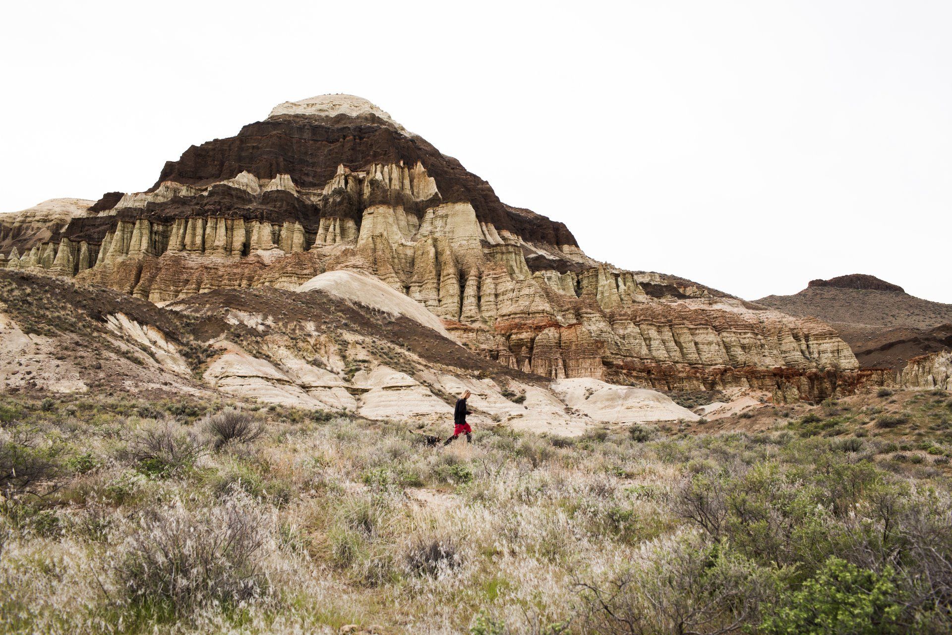 A lone hiker crosses below a unique geological feature along the Owyhee River.