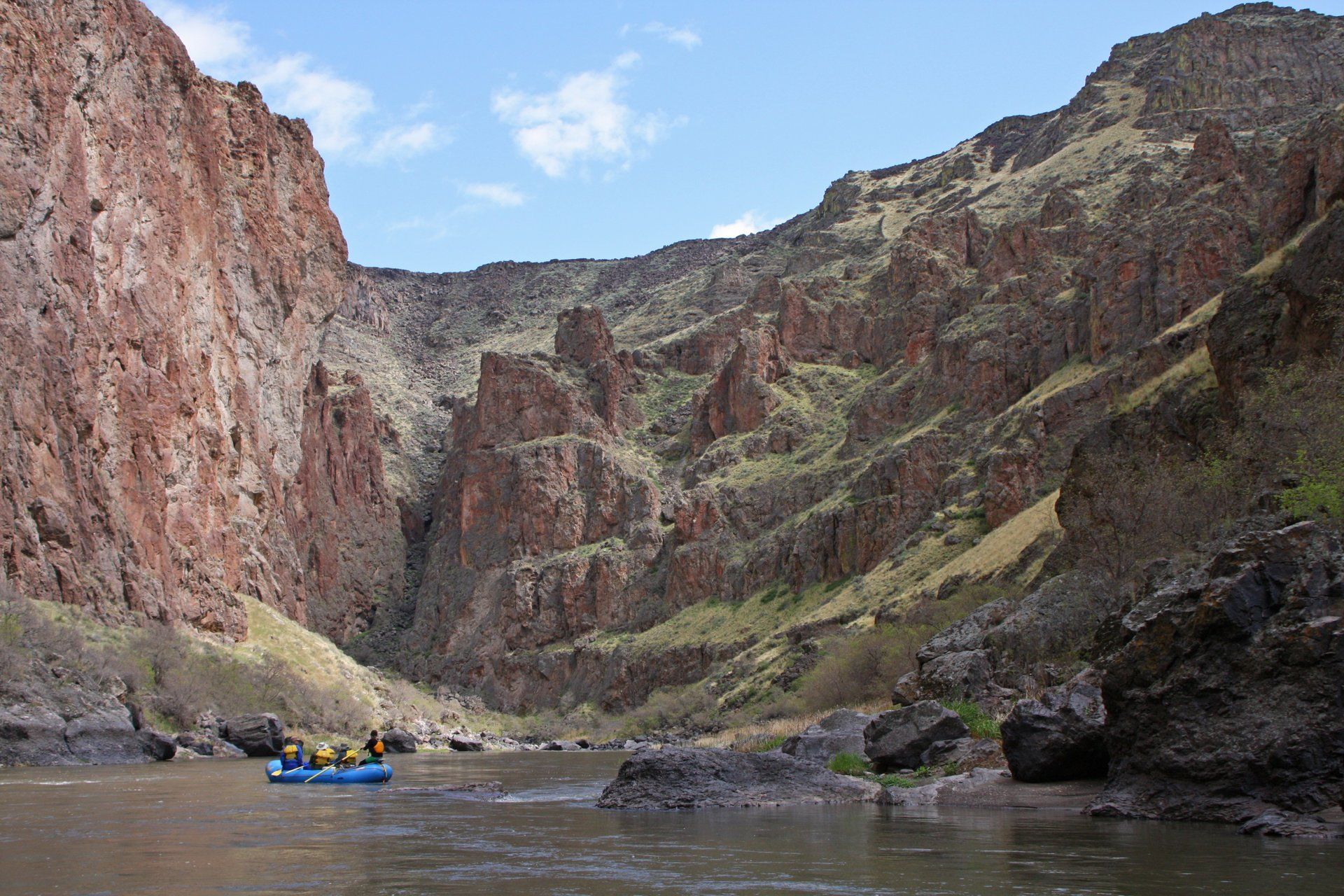 Scenic canyon walls surround a serene Ouzel raft floating on the Owyhee River.