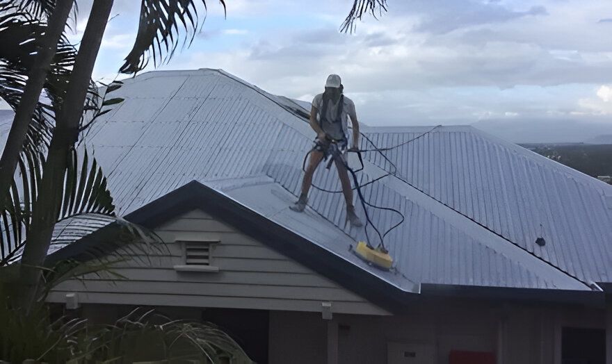 A Man is Cleaning the Roof of a House With a Vacuum Cleaner — RPS–Remote Painting Services in White Rock, QLD