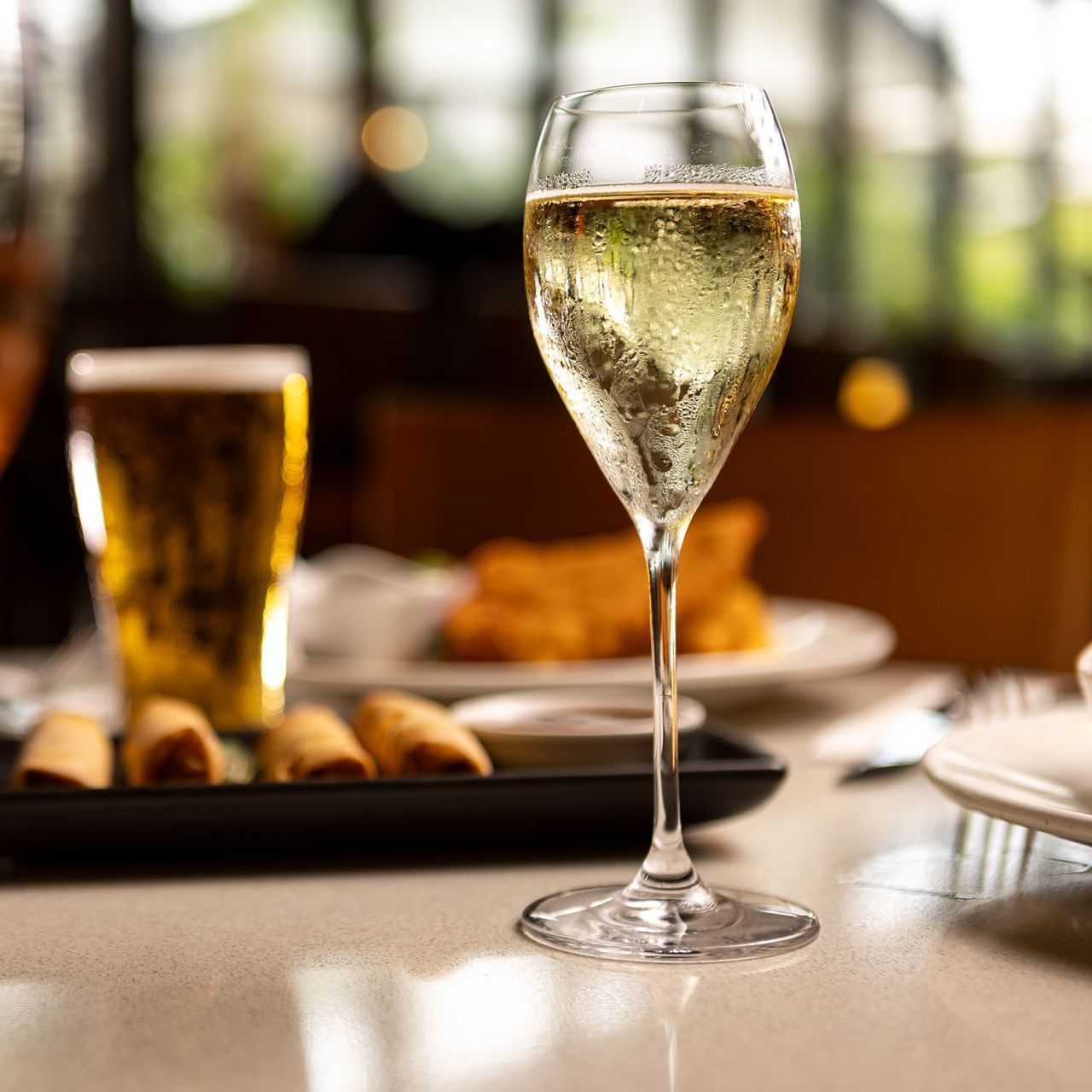 A woman is holding a glass of wine in front of a plate of food.