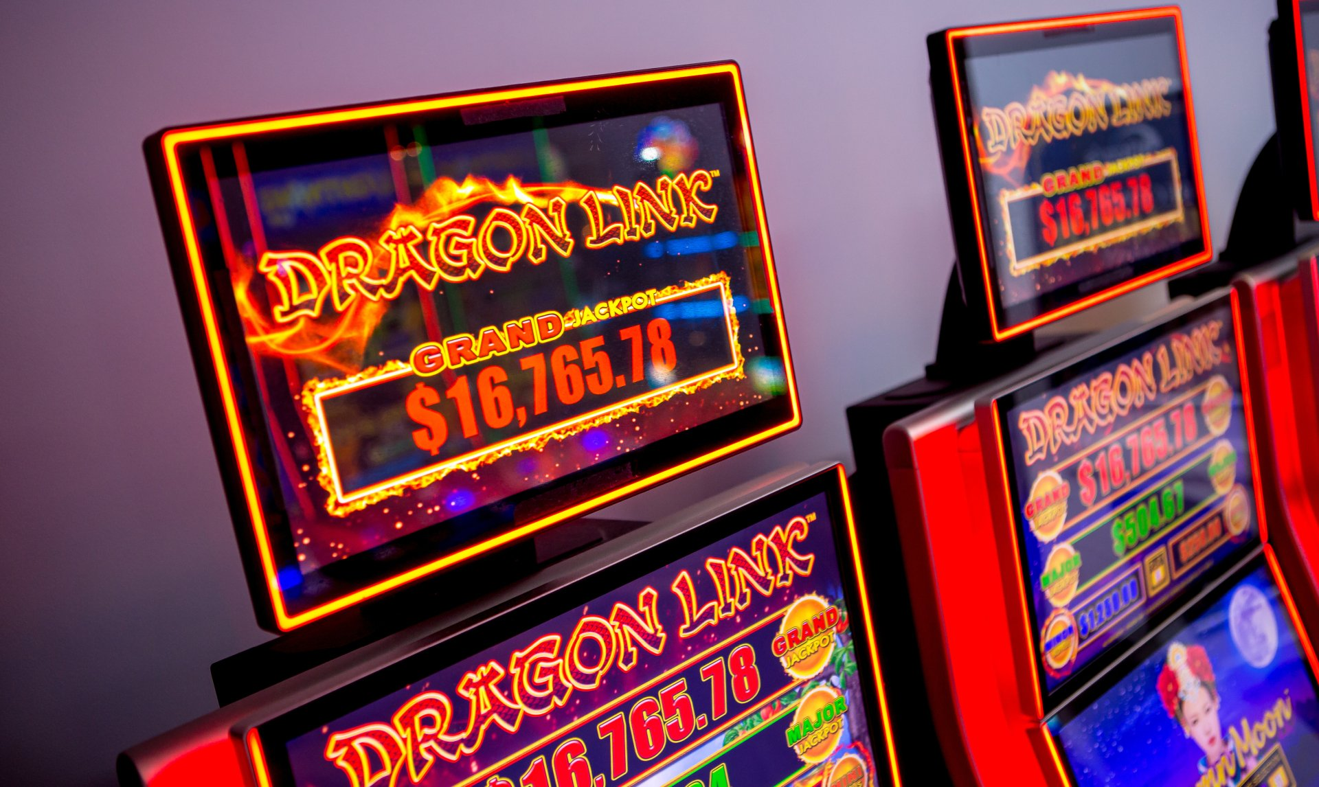 A row of slot machines with neon signs on them.