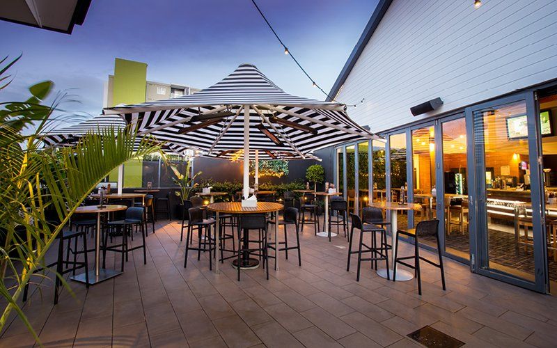 A patio with tables and chairs under striped umbrellas.