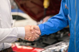 Car service, vehicle repair concept : Car service technician shaking hands with vehicle owner customer after sending car for repairing or check at automobile service center