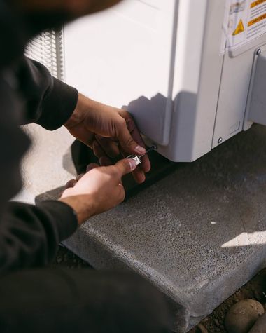 Hands adjusting a white appliance on a concrete step near a window