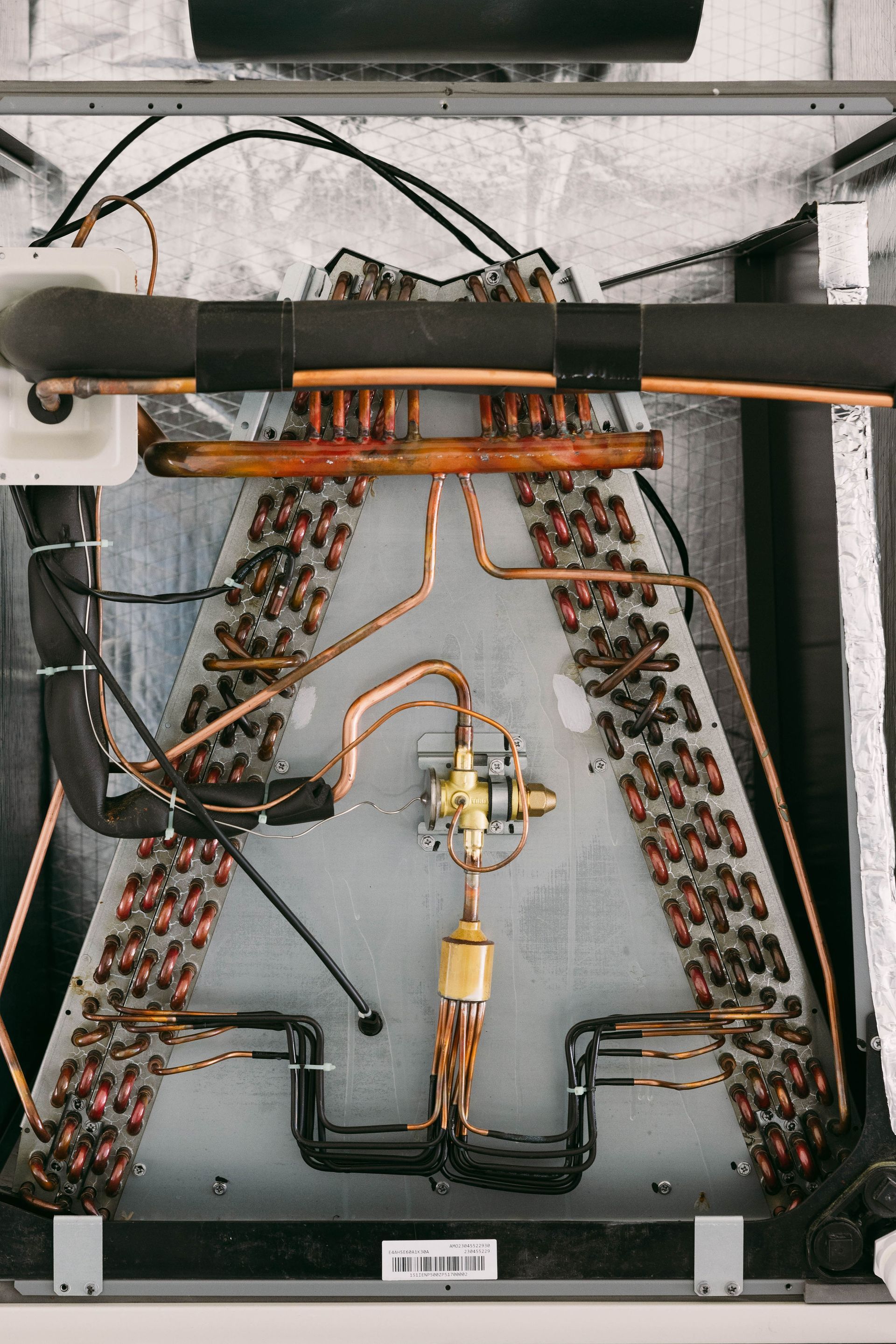 Wire harness and brass valve assembly inside a black equipment enclosure with orange cables and connectors.