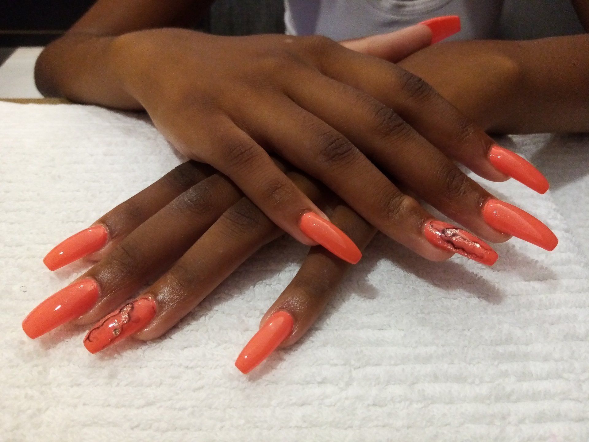 A close up of a woman 's hands with long orange nails