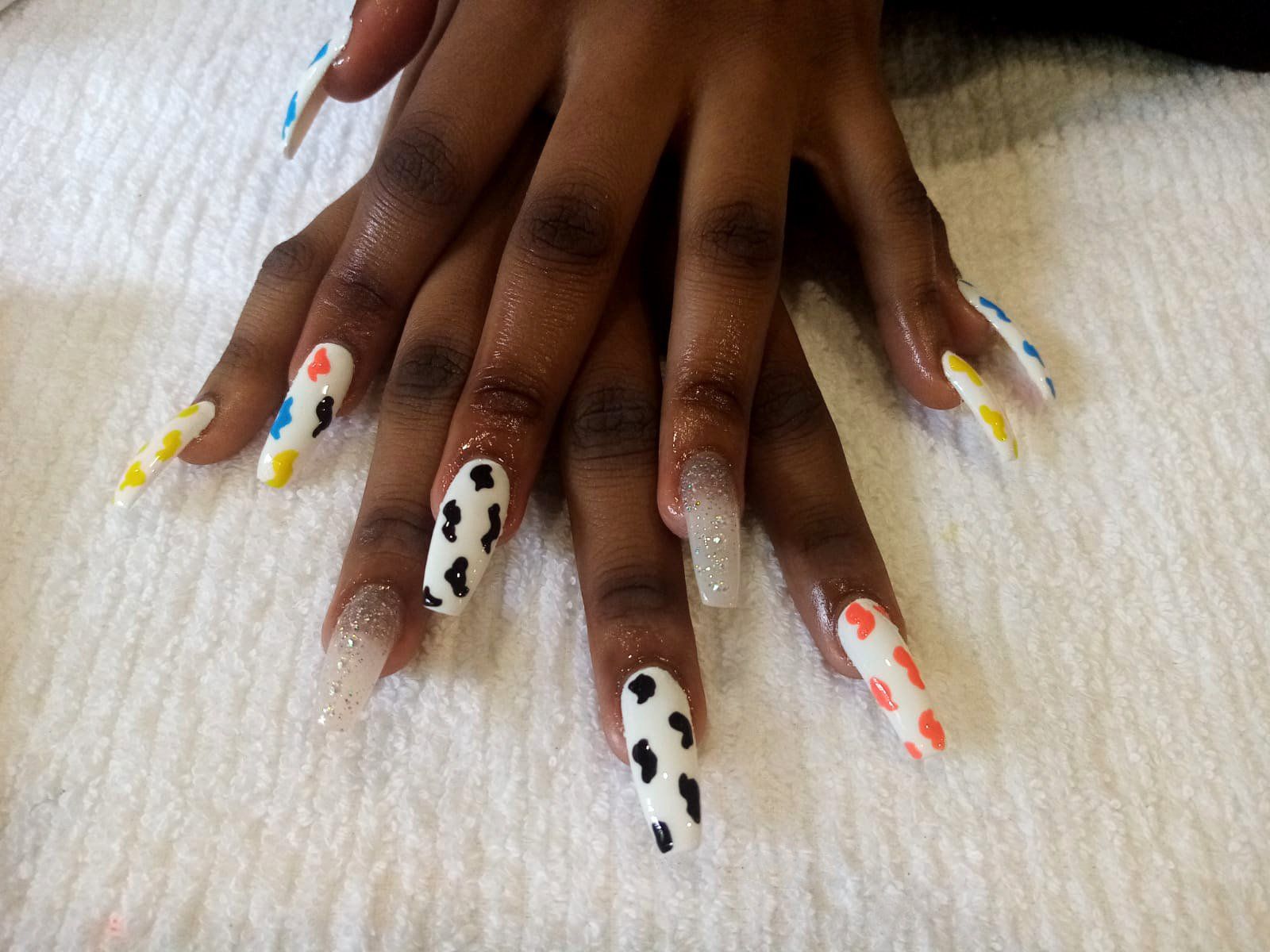 A close up of a woman 's nails with a cow print design