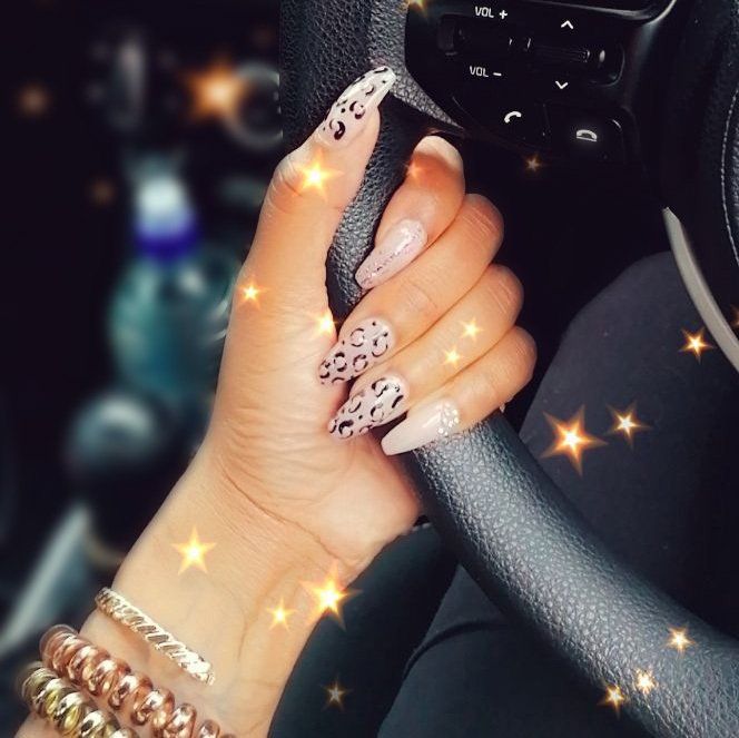 A woman with leopard print nails is holding a steering wheel