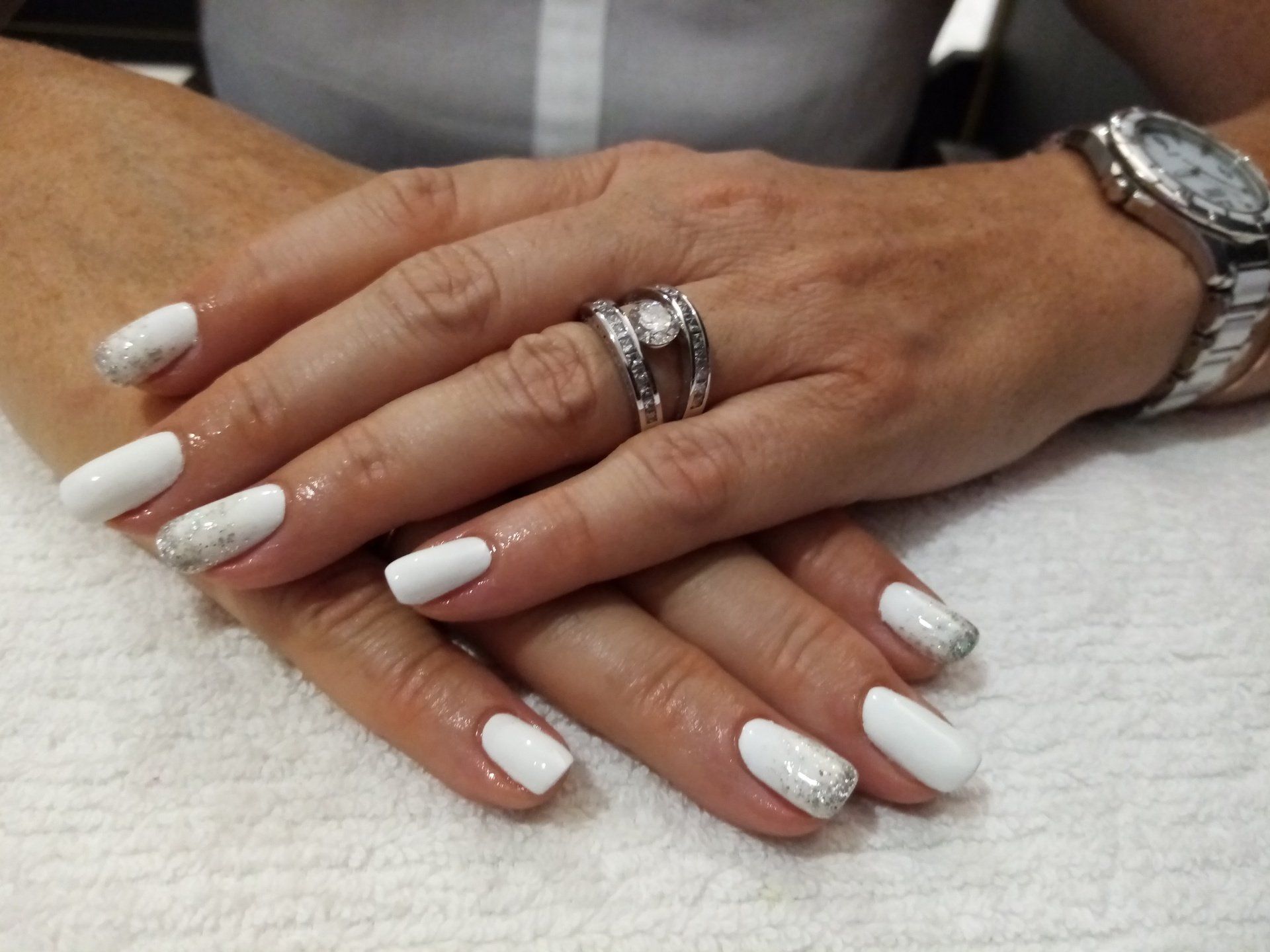 A woman 's hands with white nails and a watch on her wrist