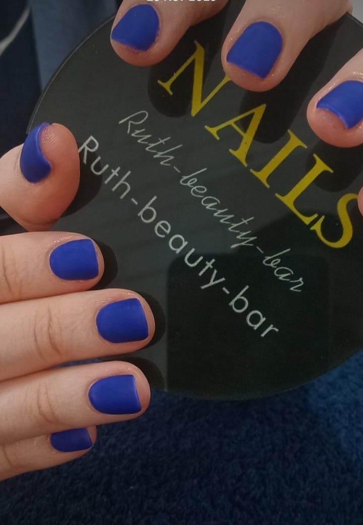 Hands with vibrant matte blue manicured nails holding a black disc branded with
