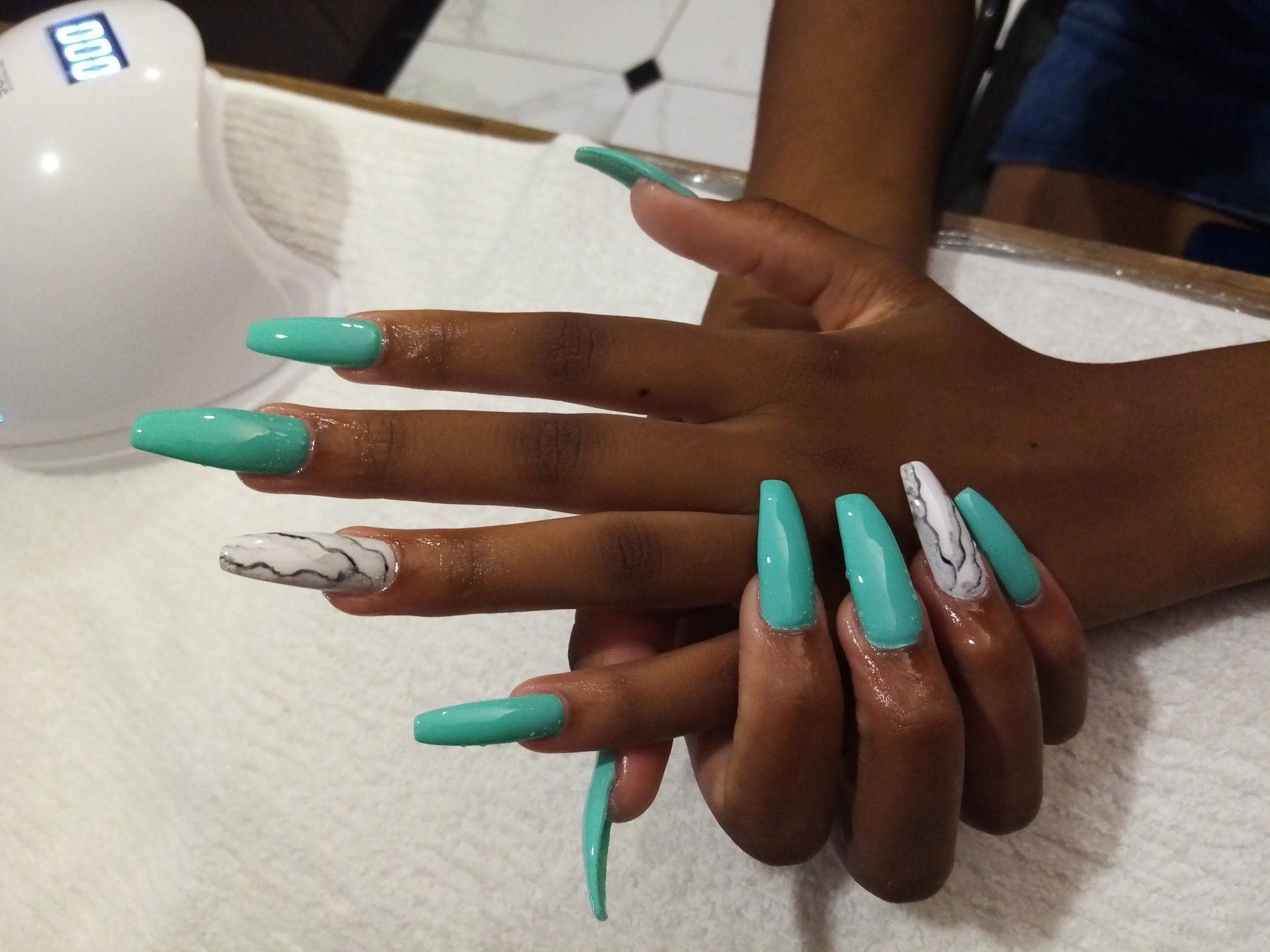 A close up of a woman 's hands with long green nails