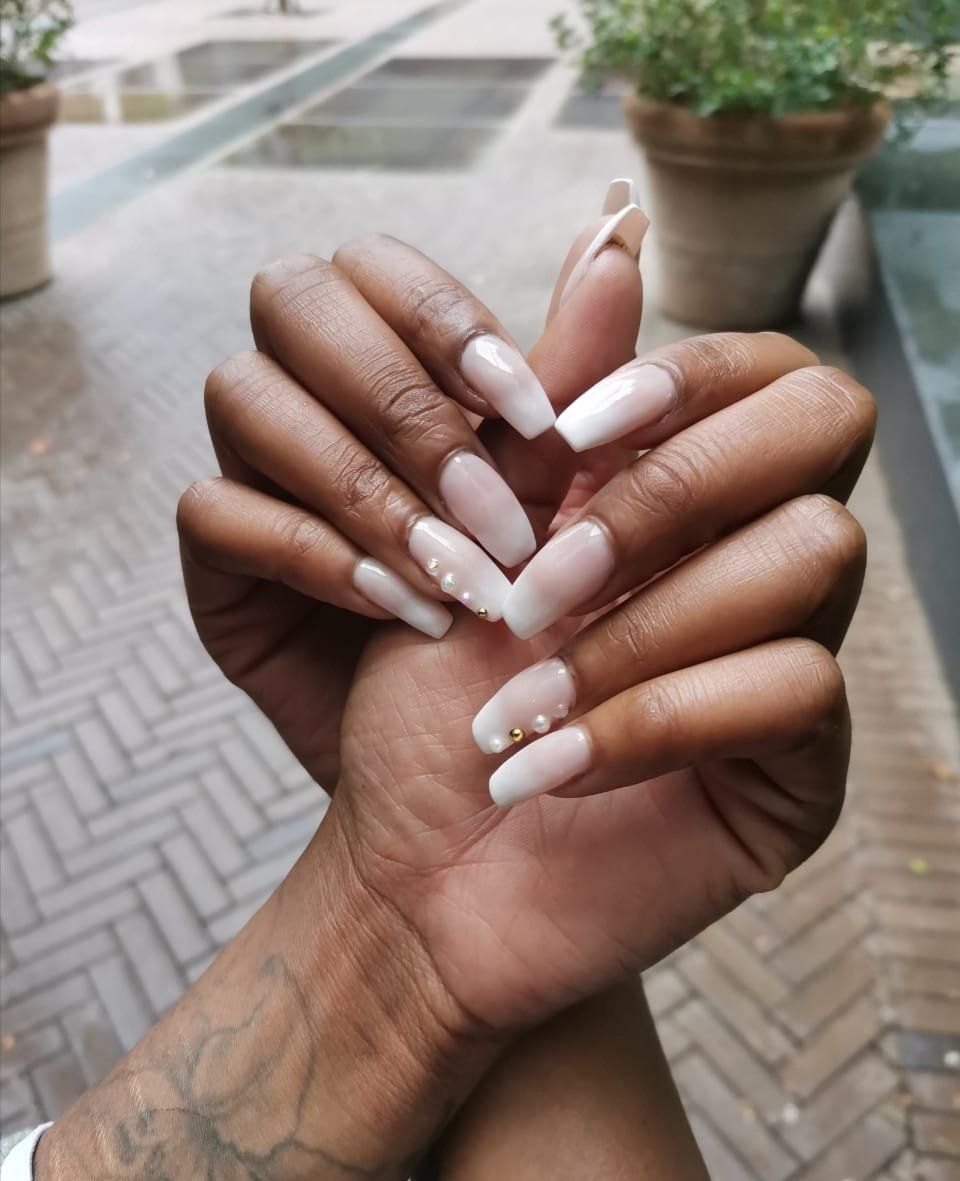 A close up of a woman 's hands with white nails