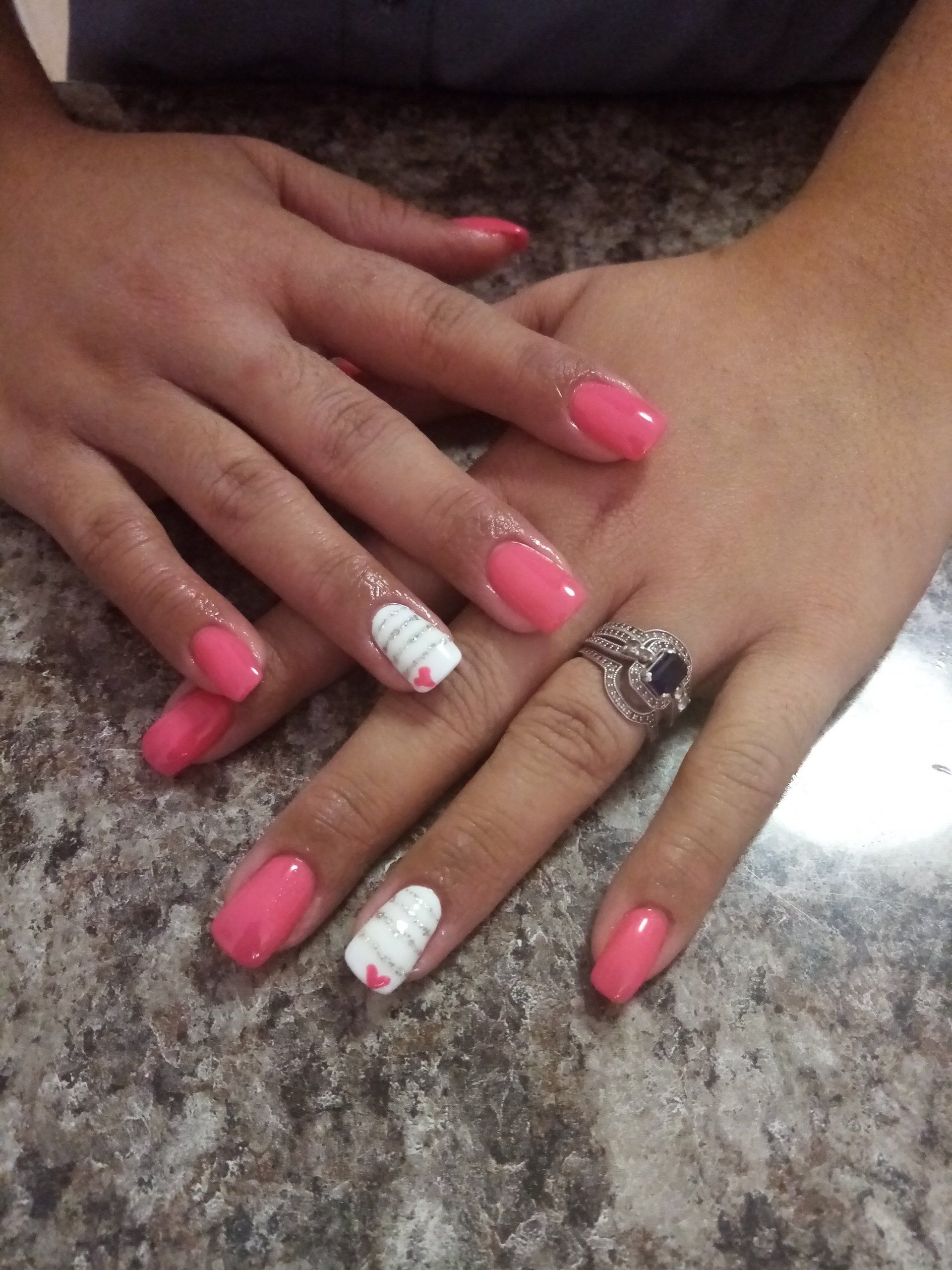 A woman 's hands with pink and white nails and a ring