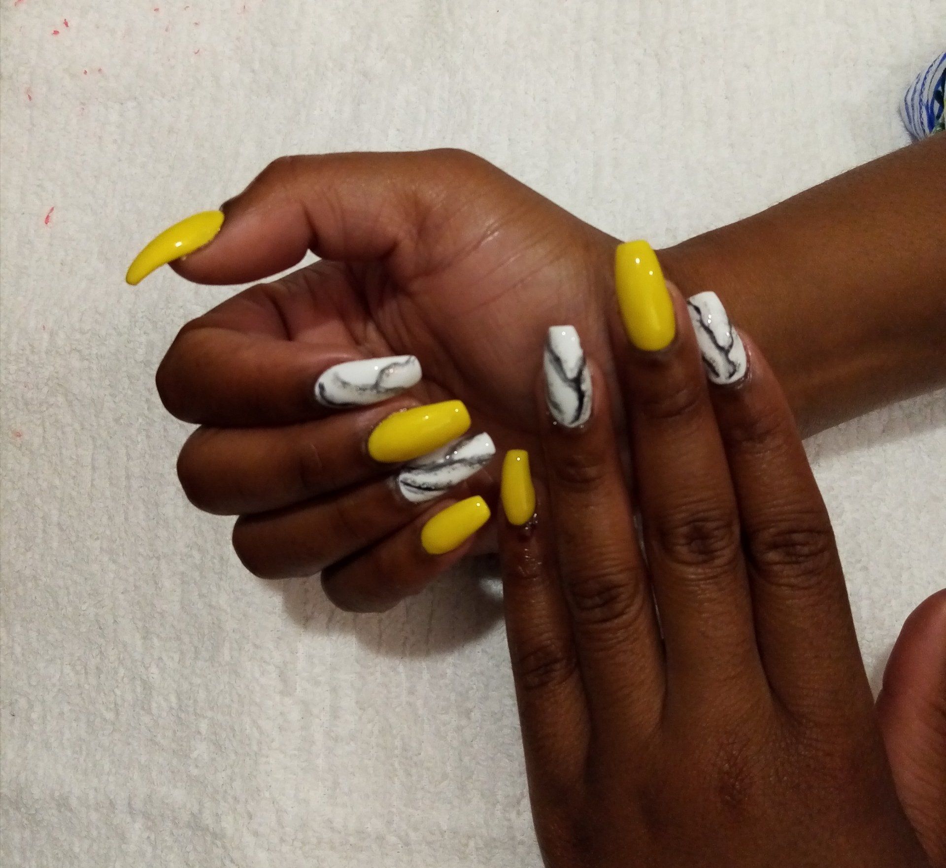 A close up of a woman 's hand with yellow and white nails