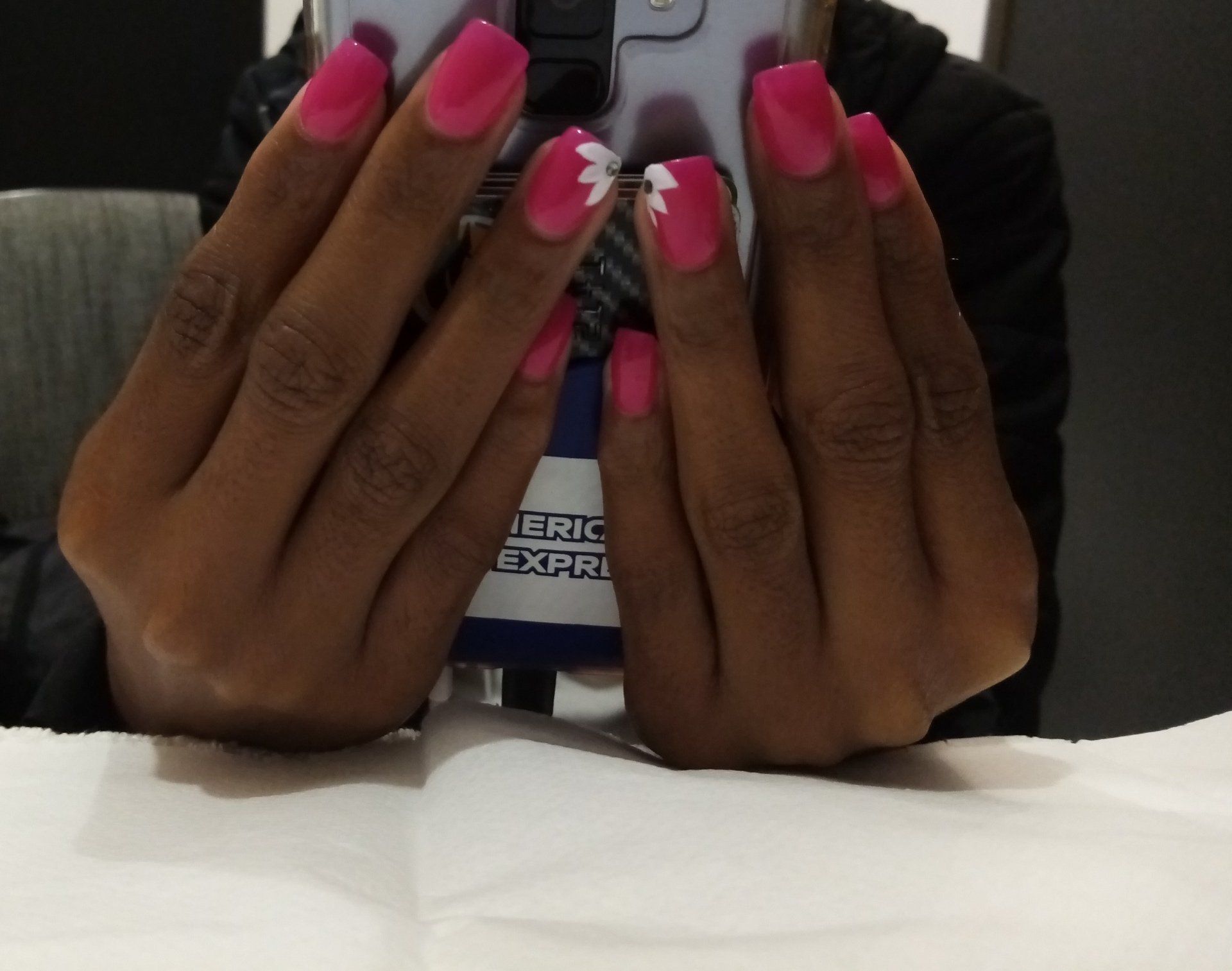 A woman with pink nails is holding a cell phone
