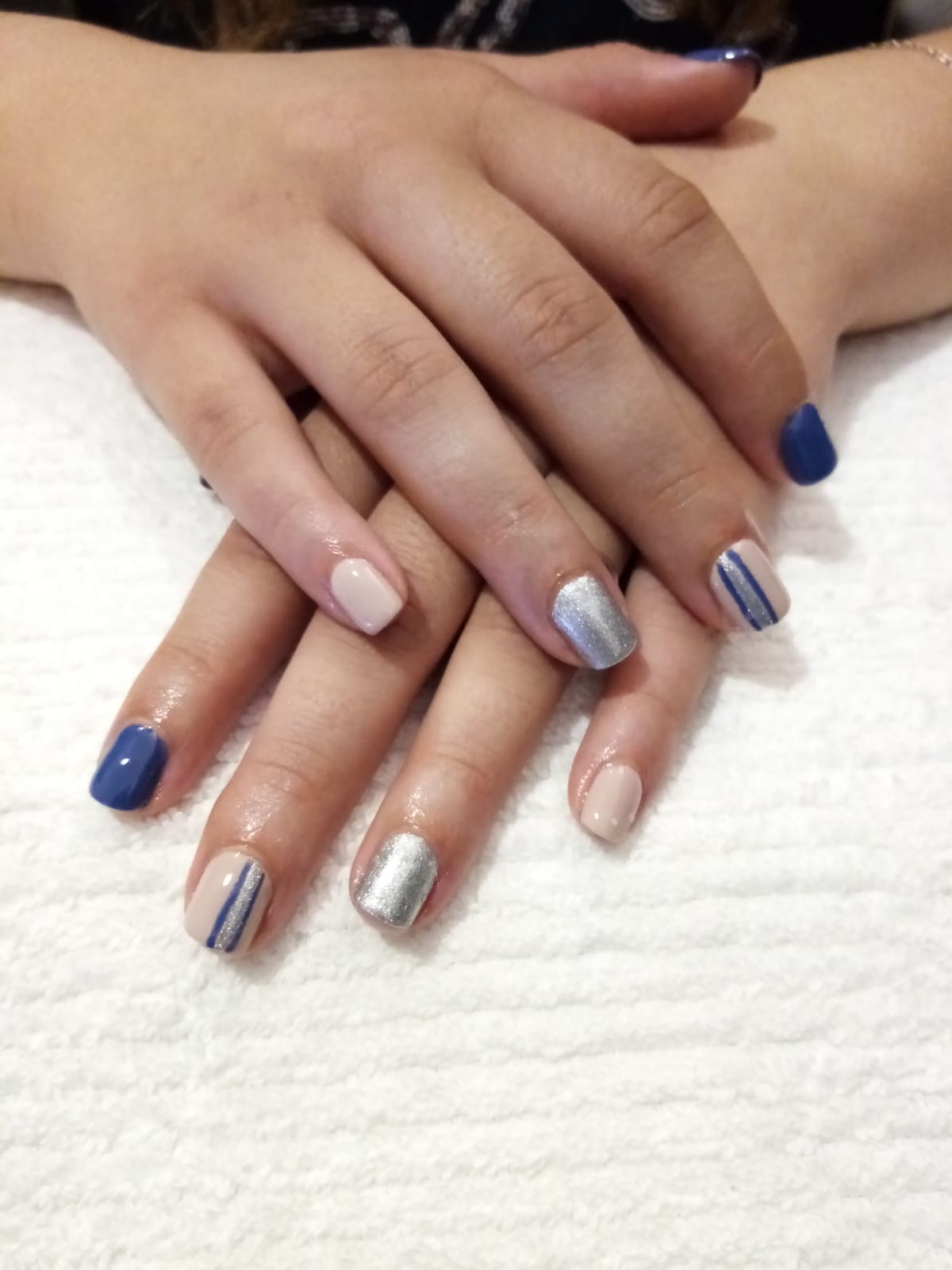 A close up of a woman 's hands with blue and silver nails