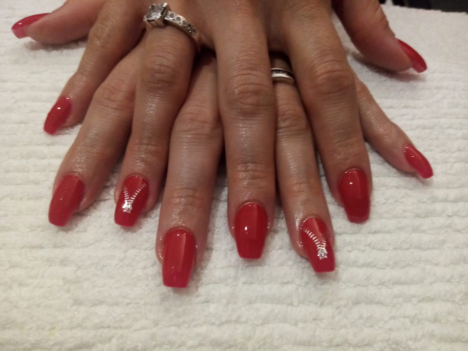 A woman 's hands with red nails and a diamond ring