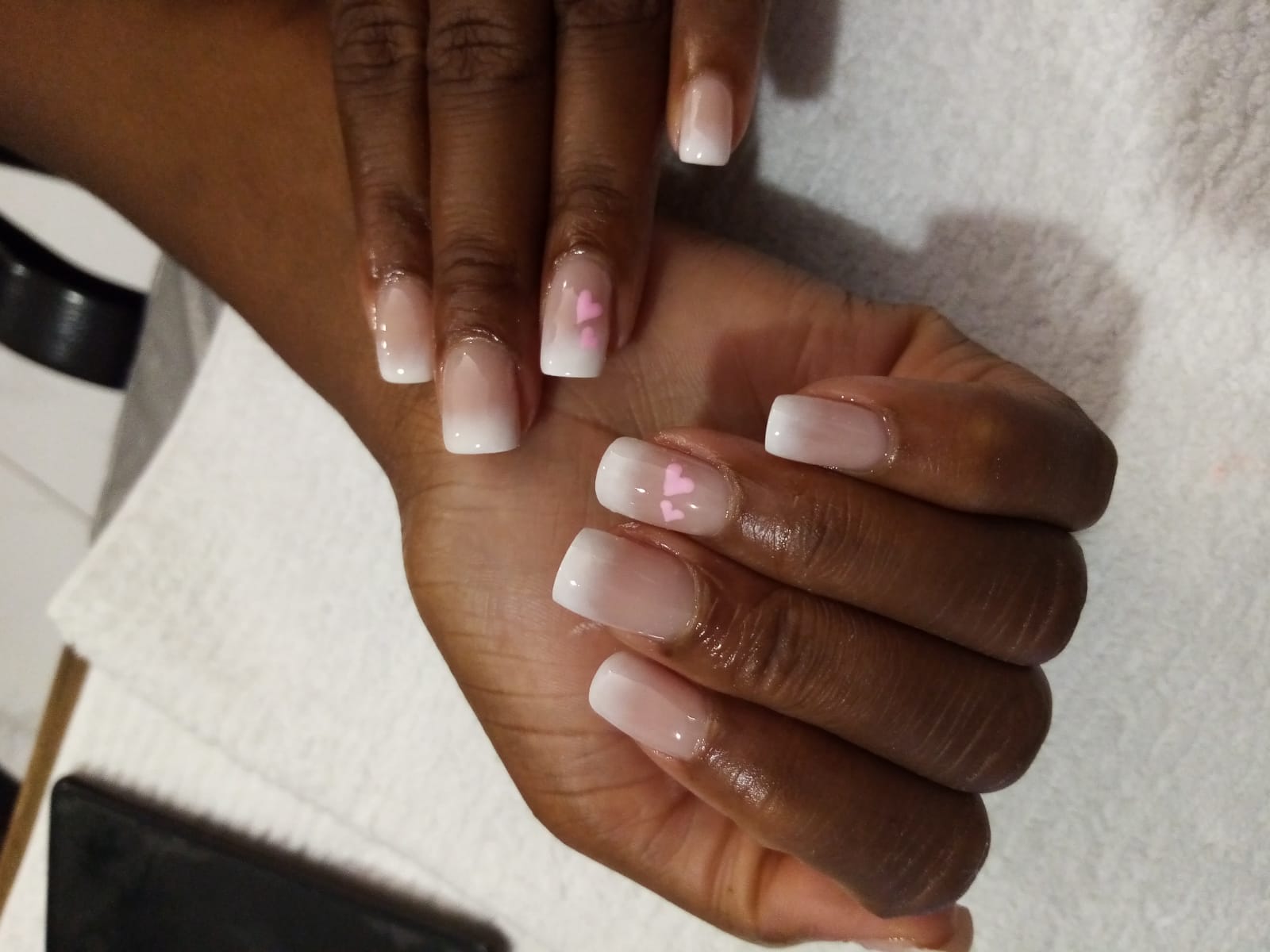 A close up of a woman 's nails with a pink heart on them
