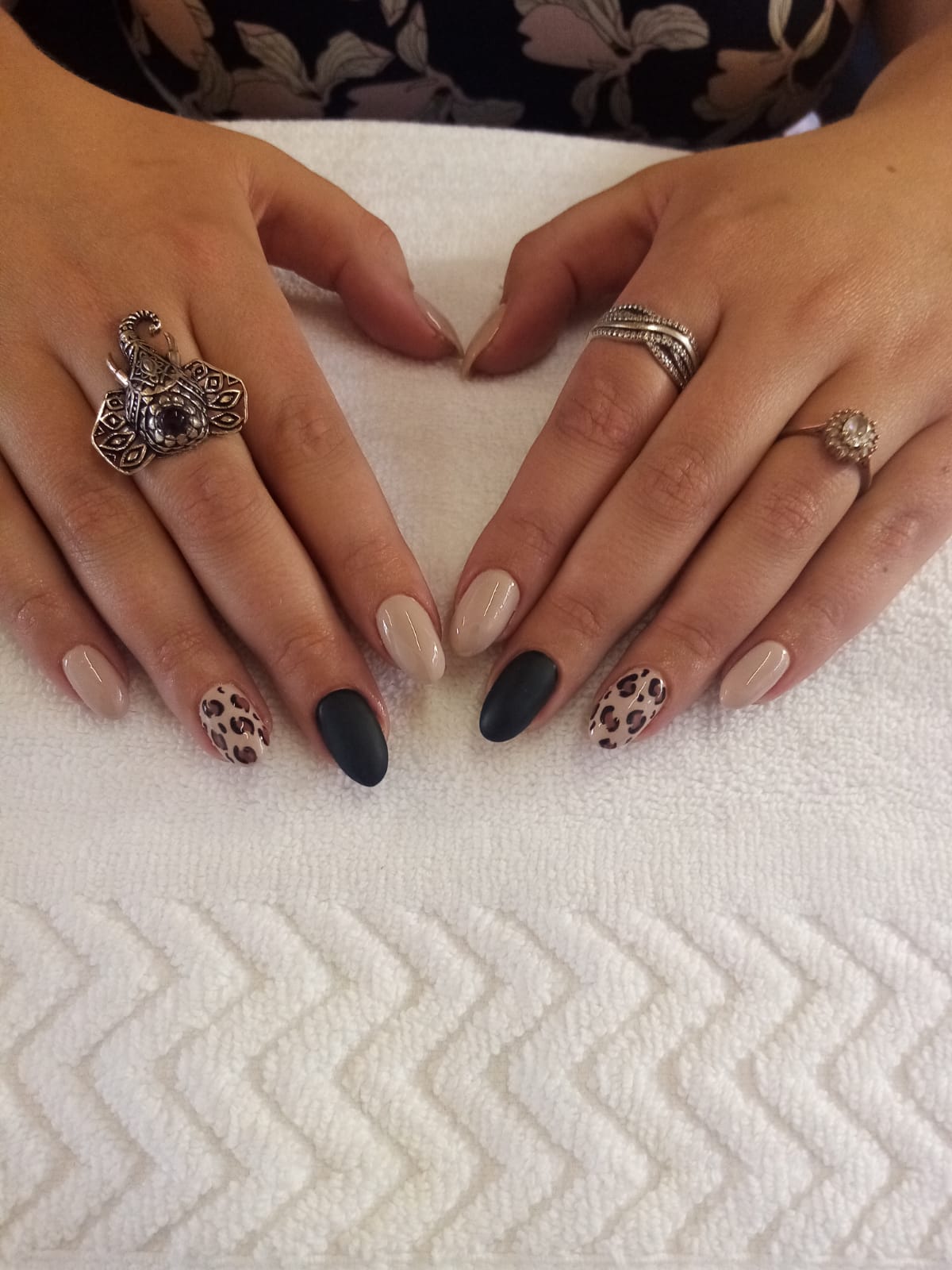 A woman 's hands with rings on them are sitting on a white towel.