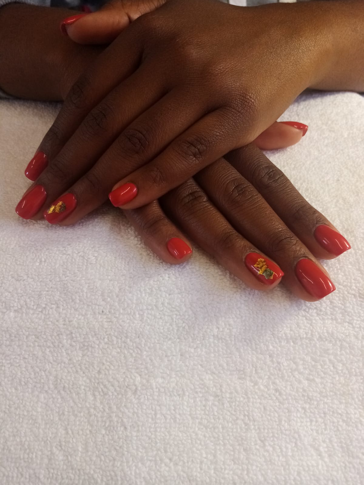 A close up of a woman 's hands with red nails on a white towel.