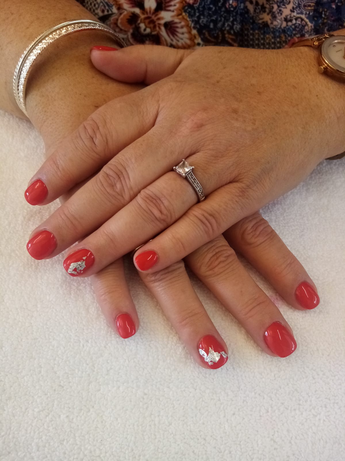 A woman 's hands with red nails and a diamond ring