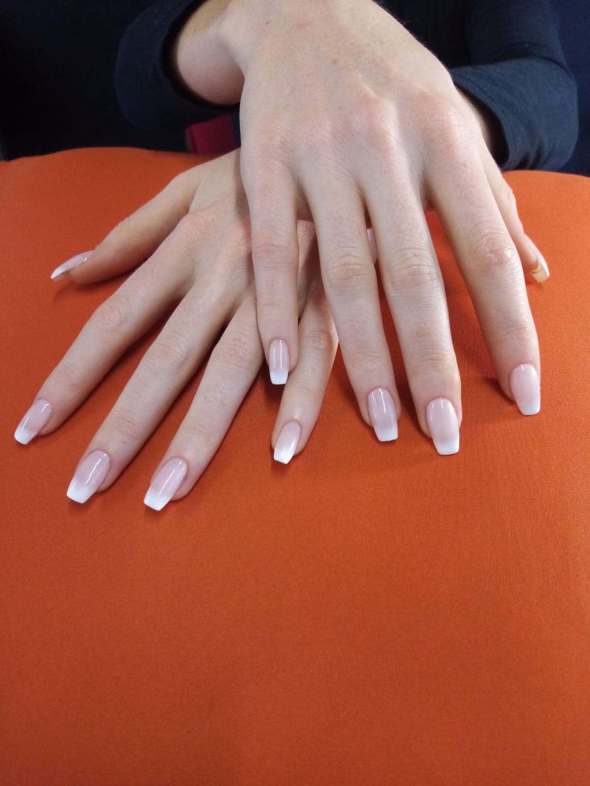 A close up of a woman 's hands with white nails