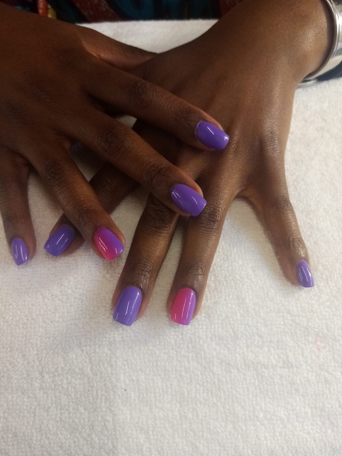 A close up of a woman 's hands with purple and pink nails