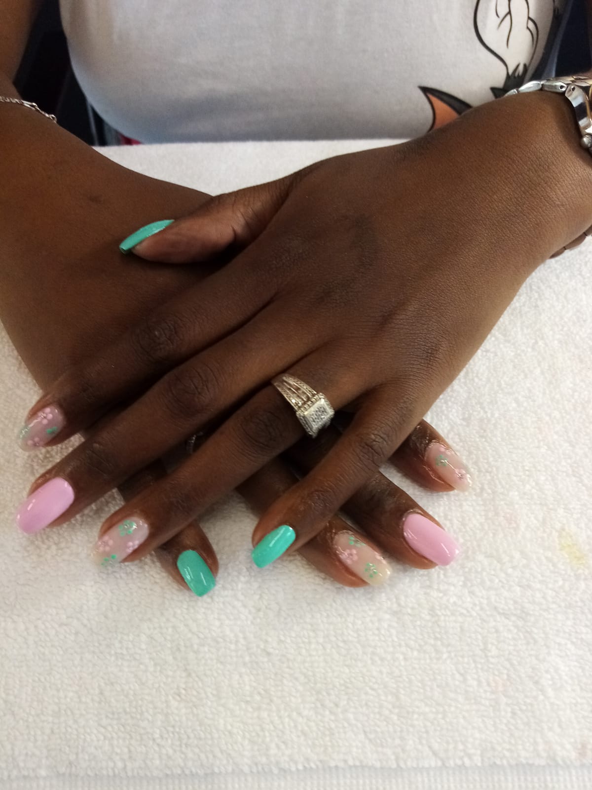 A woman 's hands with pink and green nails and a silver ring