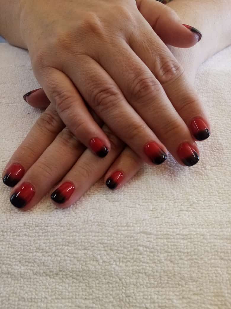 A woman 's hands with red and black nails on a white towel