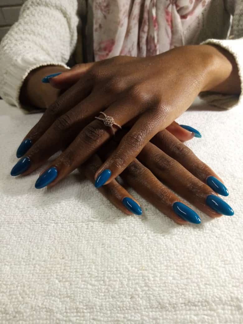 A close up of a woman 's hands with blue nails on a white towel.