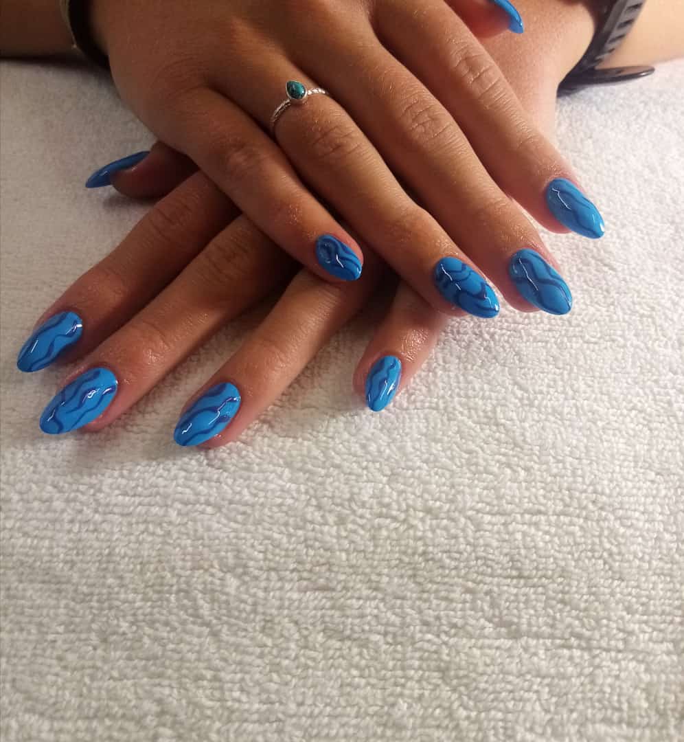 A woman 's hands with blue nails and a ring on her finger